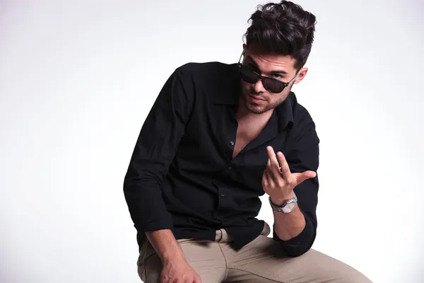 Sentado joven mirando por encima de sus gafas de sol —  Fotos de Stock