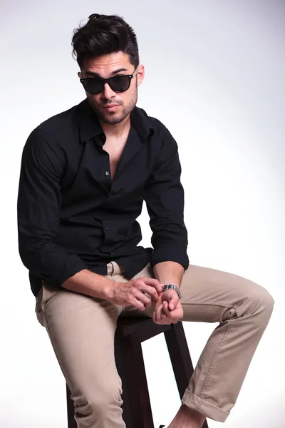 Seated young man adjusting his watch — Stock Photo, Image