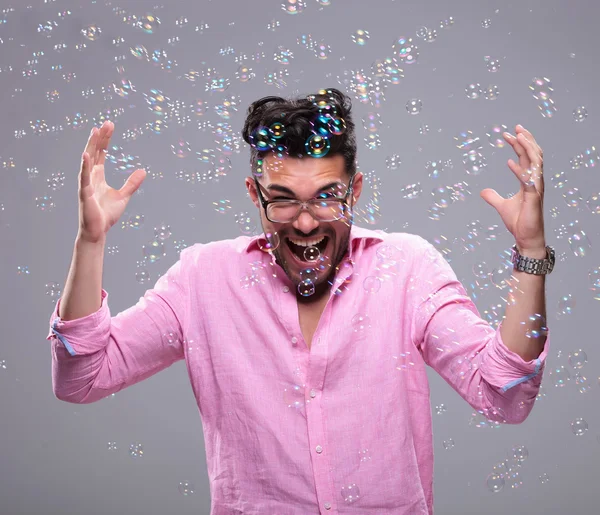 Young fashion man goes crazy among bubbles — Stock Photo, Image