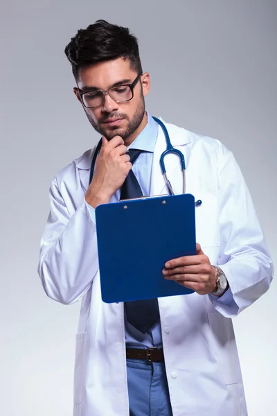 Junge Ärztin blickt besorgt auf Klemmbrett — Stockfoto