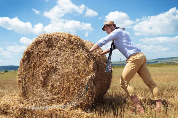 casual man outdoor pushes a haystack