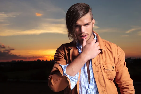 Casual man touches lip with thumb at sunset — Stock Photo, Image