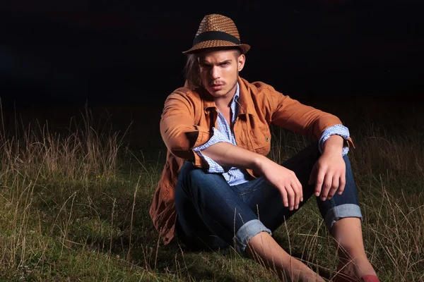 Casual man sits on grass in dark — Stock Photo, Image