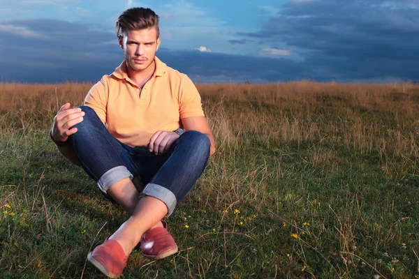 Casual man in the grass holding his knees with hands — Stock Photo, Image