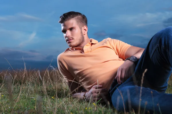 Casual man laying in the grass and looking away — Stock Photo, Image