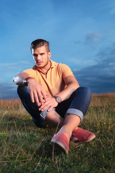 Casual man looks to side while seated in grass — Stock Photo, Image