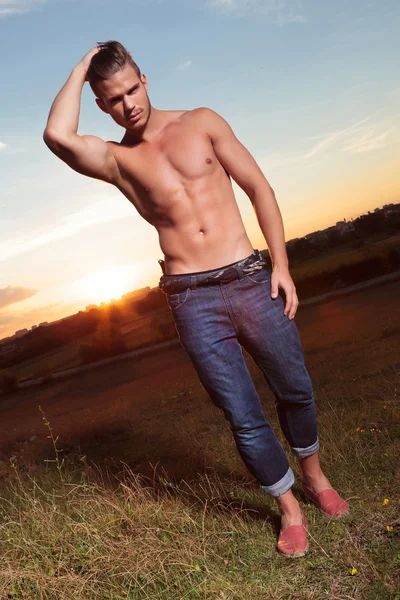 Topless man fixes his hair at sunset — Stock Photo, Image