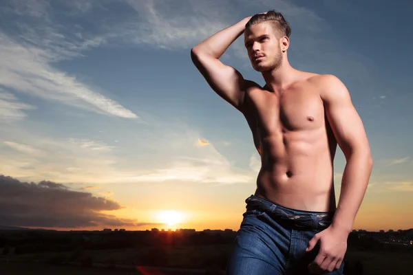 Uomo in topless passa mano attraverso i capelli al tramonto — Foto Stock