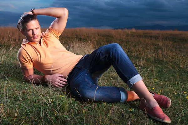 Homme occasionnel couché dans l'herbe et la fixation de ses cheveux — Photo