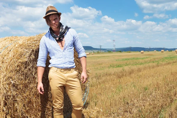 Casual man posing next to haystack — Stock Photo, Image