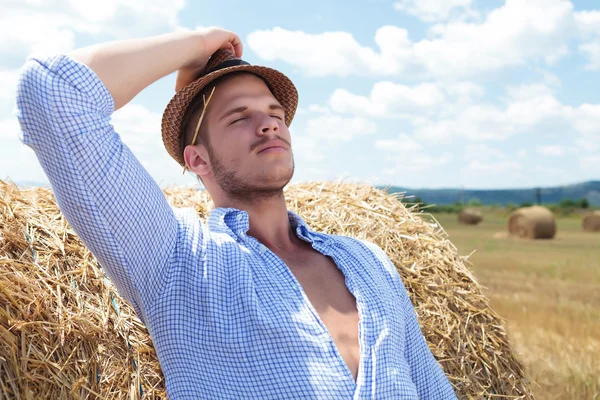 Casual man outdoor leaning back on haystack — Stock Photo, Image