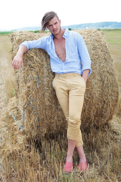 Casual man outdoor with hand in pocket and on haystack — Stock Photo, Image