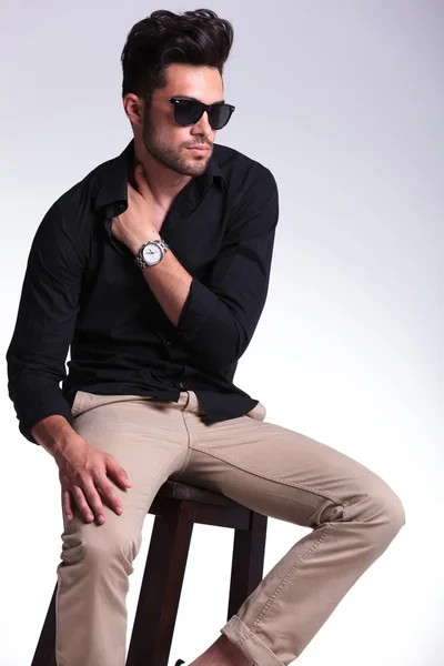 Seated young man with hand tucked in shirt Stock Photo