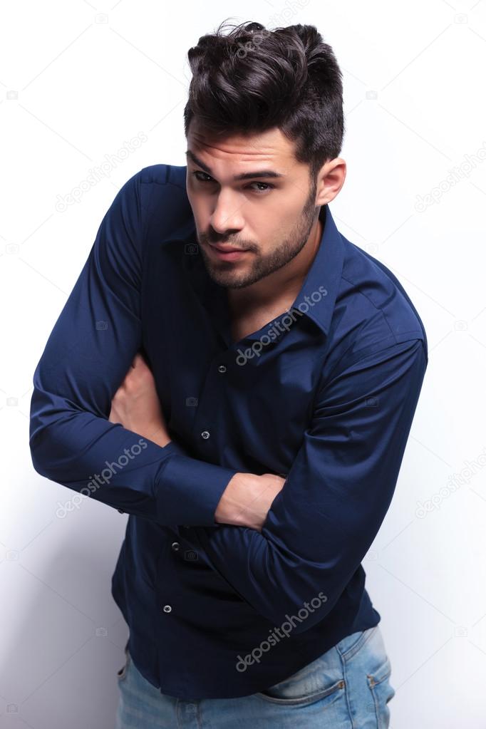 young man looks at you with arms folded