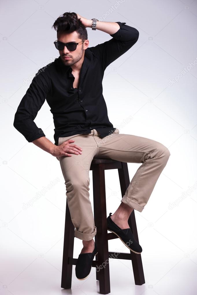 seated young man fixes his hair