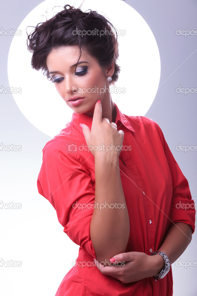 young woman looks down and touches face