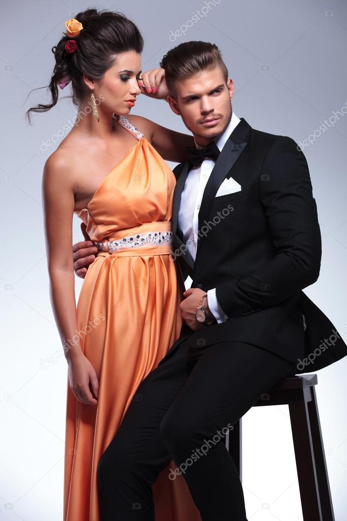 fashion couple with seated man looking away