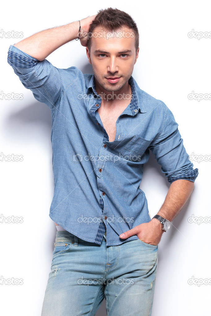serious casual man poses with hand on head and in pocket