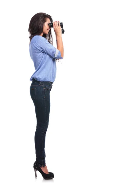 Lado de uma mulher casual olhando através de binóculos — Fotografia de Stock