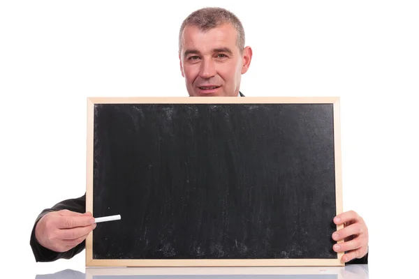 Homem de negócios apresenta com giz no pequeno quadro negro — Fotografia de Stock
