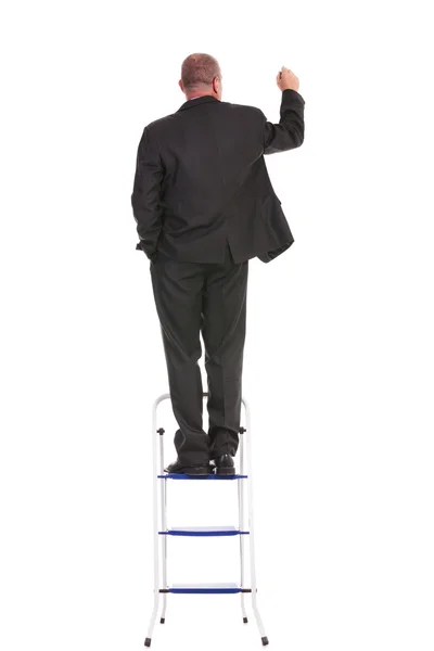 Achterkant van zakenman schrijven op een ladder — Stockfoto