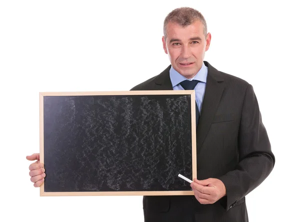 Homem de negócios aponta com giz no quadro negro — Fotografia de Stock