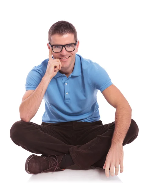 Seated casual man smiles with hand on cheek — Stock Photo, Image