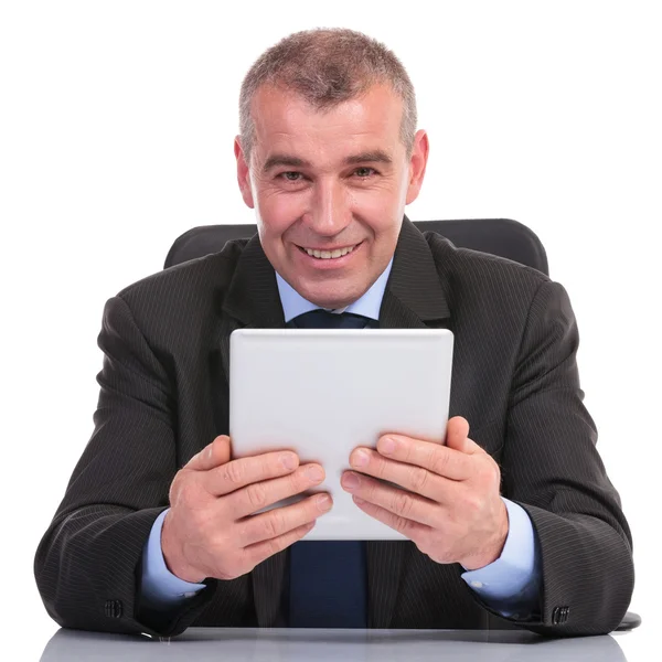 Hombre de negocios sosteniendo una tableta en su escritorio — Foto de Stock