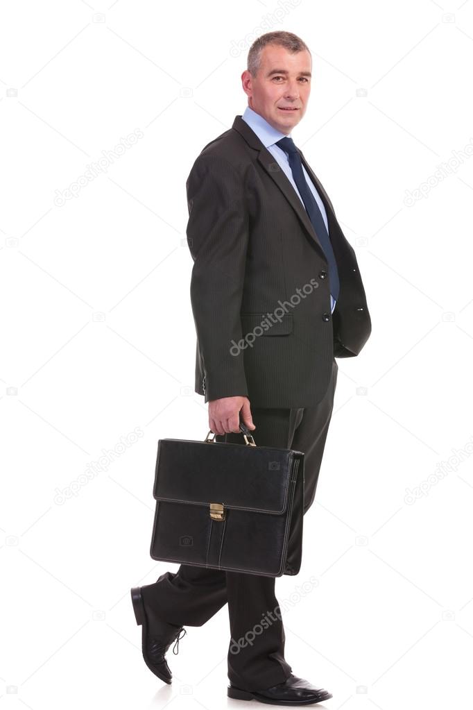 business man walks with briefcase and looks at you