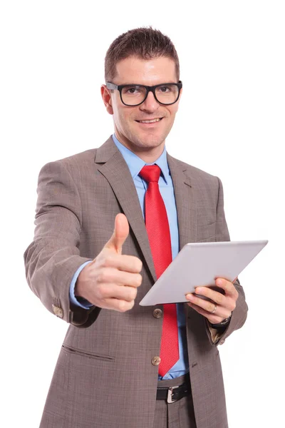 Joven hombre de negocios sostiene la tableta y muestra el pulgar hacia arriba — Foto de Stock