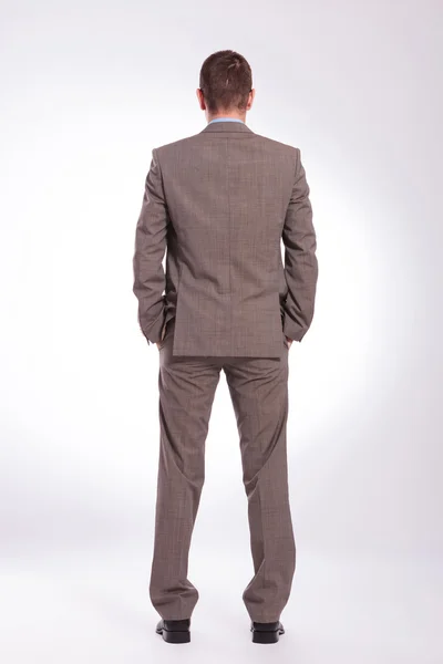 Espalda de un joven hombre de negocios con ambas manos en los bolsillos — Foto de Stock