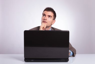 dalgın genç iş adamı arkasında laptop uzakta görünüyor