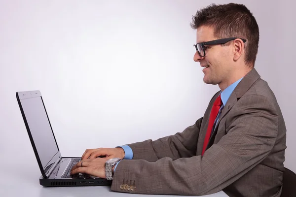 Сторона молодого бизнесмена, работающего на ноутбуке — стоковое фото