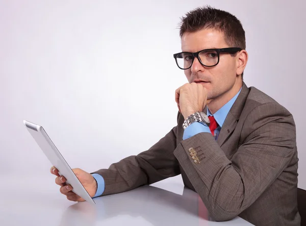 Side of pensive young business man with tablet looking at you — Stock Photo, Image