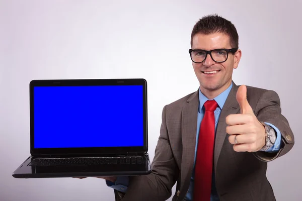 Jovem homem de negócios apresenta laptop com polegar para cima — Fotografia de Stock