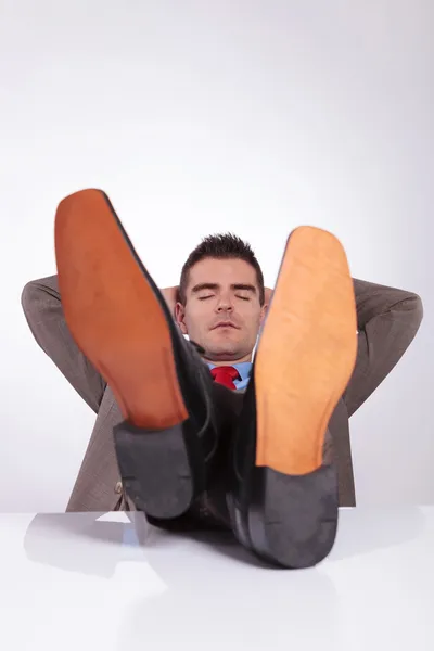 Jeune homme d'affaires dort avec les pieds sur le bureau — Photo