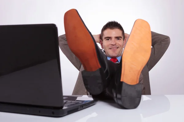 Young business man looks at you with hands behind head — Stock Photo, Image