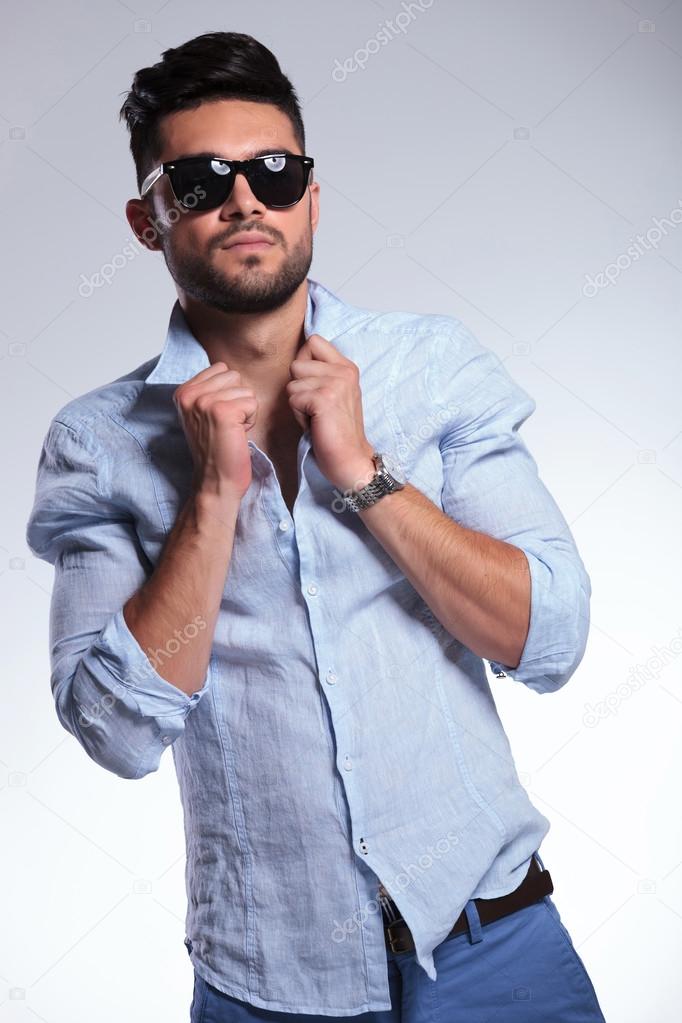 casual man adjusting his shirt and looking at you