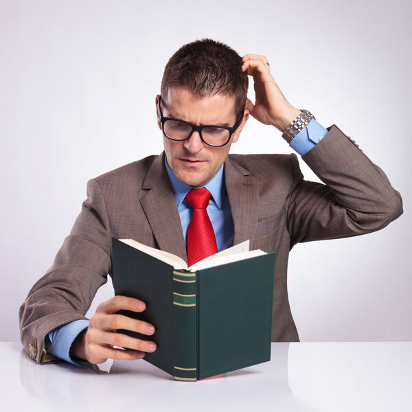 young business man reads a book and scratches his head