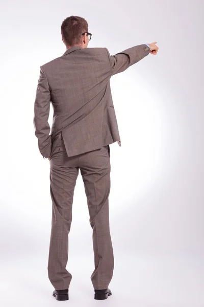 Back of a young business man pointing with a hand in pocket — Stock Photo, Image