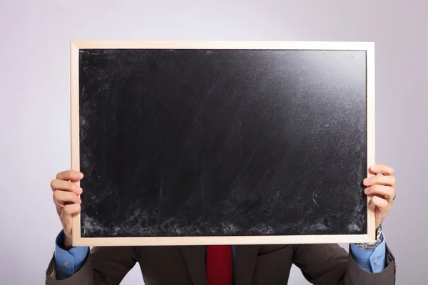 Young business man holds blackboard in front of his face — Stock Photo, Image