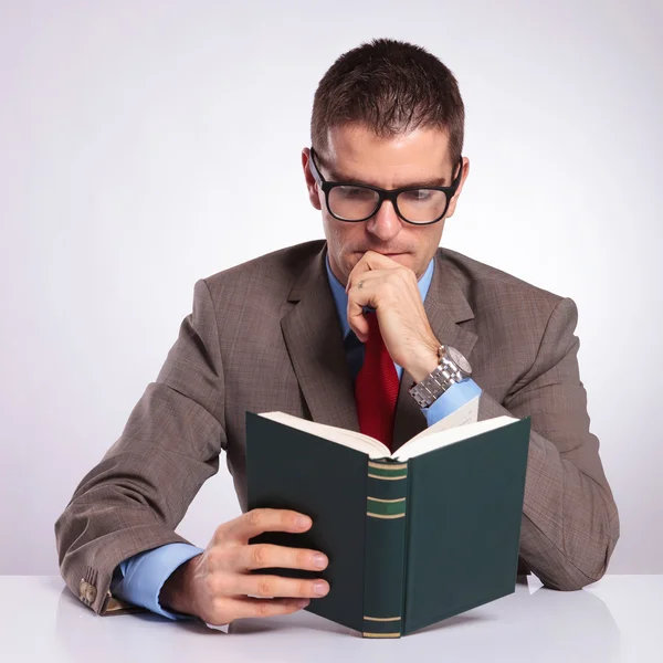 Jovem homem de negócios lendo um livro em sua mesa — Fotografia de Stock