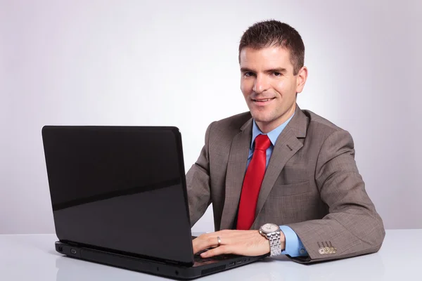 Junger Geschäftsmann schaut dich an, während du am Laptop arbeitest — Stockfoto