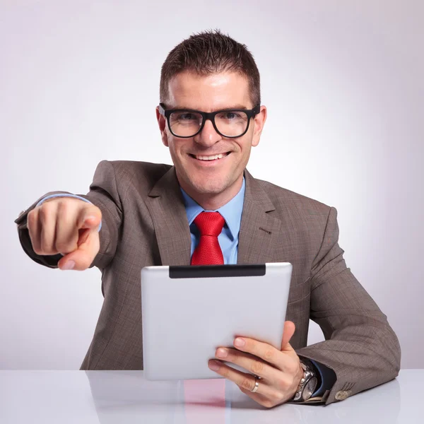 Young business man with tablet points at you and smiles — Stock Photo, Image