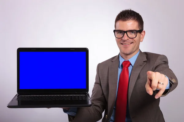 Young business man presents a laptop and points at you Stock Image