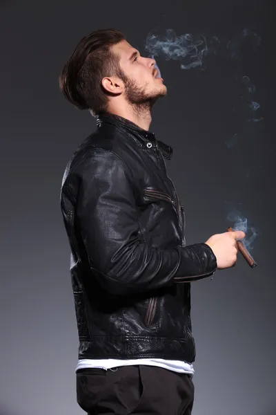 Man in leather jacket smoking and blowing the smoke — Stock Photo, Image