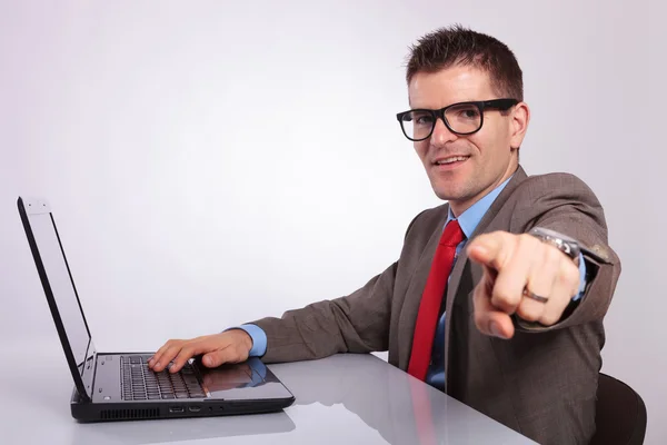 Side of young business man at laptop, pointing at you — Stock Photo, Image