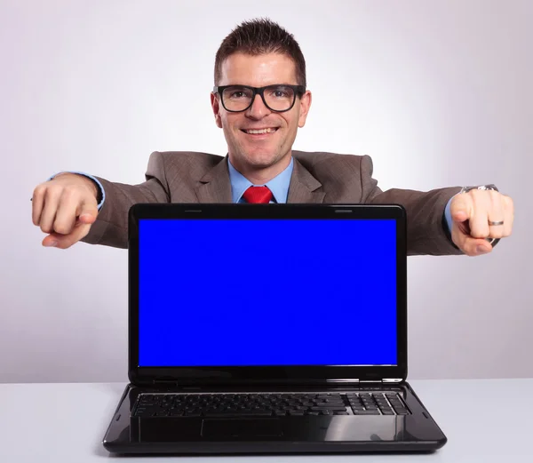 Young business man presents laptop and points with both hands at Royalty Free Stock Photos