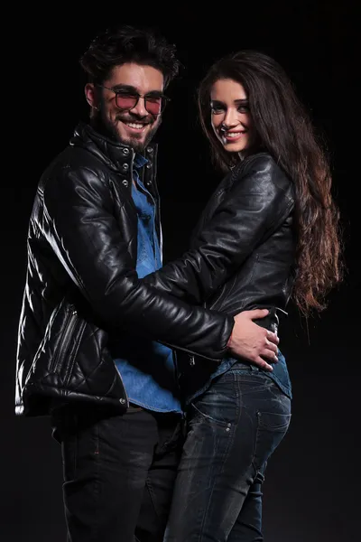 Casal em jaqueta de couro de pé abraçado e sorriso — Fotografia de Stock