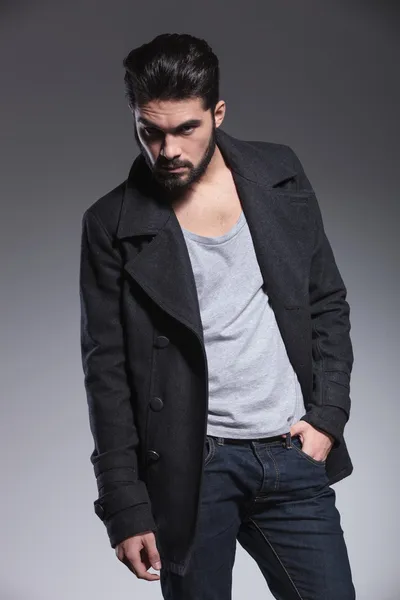 Young bearded man in long coat is posing — Stock Photo, Image